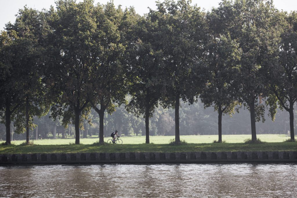 man on bicycle rides along amsterdam rijn kanaal in the netherlands