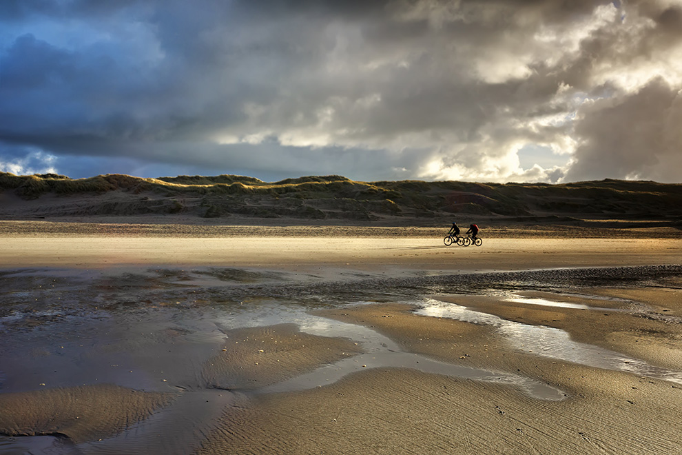 sport cyclists on north sea beach